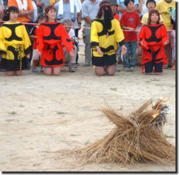 Festival cheerleaders look on as fire is lit